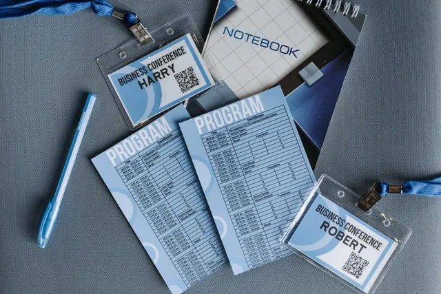 Flat lay of business conference materials including name tags, program, notebook, and pen. Jak potwierdzić adres i lokal działania firmy w rejestrach i ewidencjach